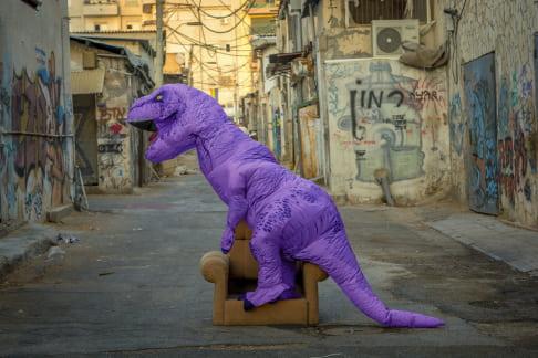 Purple dinosaur sitting on a couch in Florentin neighborhood, Tel Aviv